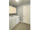 Well-lit laundry room with a washer, dryer, overhead storage, and a neutral-toned striped rug at 12231 Valley View Cir, Indianapolis, IN 46229