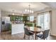Bright kitchen with stainless steel appliances, green cabinetry, and a cozy dining area at 12444 Bearsdale Dr, Indianapolis, IN 46235