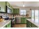 Updated kitchen boasts stainless steel appliances, mosaic tile backsplash, and stylish green cabinetry at 12444 Bearsdale Dr, Indianapolis, IN 46235