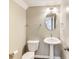 Cozy powder room with pedestal sink, oval mirror, and modern lighting at 13050 Grand Vue Dr, Carmel, IN 46032
