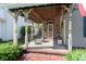 Inviting covered porch features a cozy seating area and brick pathway to the house entrance at 1352 Clinton St, Noblesville, IN 46060