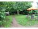 Landscaped backyard with pathway, orange umbrella, and grill at , Indianapolis, IN 46220