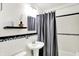 Bathroom featuring a sleek pedestal sink, black and white tile accents, and modern fixtures at 1868 N Hawthorne Ln, Indianapolis, IN 46218