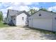 View of the exterior of a detached garage with an overhead door and siding, as well as gravel driveway at 202 S Church St, Brooklyn, IN 46111