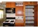 Kitchen area featuring a range, microwave, wooden cabinets and a pantry at 202 S Church St, Brooklyn, IN 46111