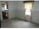 Empty living room featuring a window, neutral carpet, and dated wainscoting at 202 S Church St, Brooklyn, IN 46111