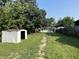 View of a large backyard with mature trees, a storage shed, a swing set, and a house in the background at 2310 E Raymond St, Indianapolis, IN 46203
