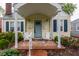 Charming house featuring brick porch with Adirondack chairs, a light blue front door, and manicured landscaping at 28 N Elizabeth St, Indianapolis, IN 46219