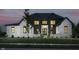 Stunning two-story home featuring white brick and dark vertical siding at dusk at 3713 Cherwell Dr, Zionsville, IN 46077