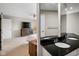 Modern bathroom with double sinks, a dark countertop, and a view into the carpeted bedroom at 3975 Offshore Dr, Columbus, IN 47203