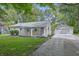 Inviting single-story home with a gravel driveway leading to a detached garage, surrounded by lush greenery and mature trees at 420 Vista Dr, Carmel, IN 46280