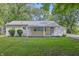 Charming single-story home featuring a light yellow exterior, well-manicured lawn, and a detached garage nestled among mature trees at 420 Vista Dr, Carmel, IN 46280
