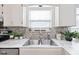 Well-lit kitchen sink featuring a mosaic backsplash, stainless steel faucet, and white marble-style countertops at 4736 Rocky Knob Ln, Indianapolis, IN 46254