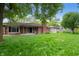 Spacious backyard with green lawn, mature trees, brick house, and a separate storage shed at 4904 N Tillotson Ave, Muncie, IN 47304