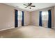 Bedroom featuring neutral carpet, tan walls, ceiling fan, and large windows with blue curtains at 4904 N Tillotson Ave, Muncie, IN 47304