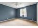 Bedroom featuring neutral carpet, blue walls, white ceiling fan, and window with white curtains at 4904 N Tillotson Ave, Muncie, IN 47304