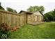 Fenced backyard and stone exterior of the home with red roses along the wooden fence and well-manicured lawn at 5331 Birch Ln, Greenwood, IN 46143