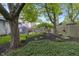 Large, landscaped backyard with mature trees, garden area, grass, and patio furniture under a blue umbrella at 5543 N Pennsylvania N St, Indianapolis, IN 46220