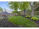 Lush green backyard with lawn, dining patio, and beautiful garden beds with a wooden fence at 5543 N Pennsylvania N St, Indianapolis, IN 46220