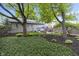 Expansive backyard with mature trees, green lawn, mulched beds, and a patio dining area at 5543 N Pennsylvania N St, Indianapolis, IN 46220