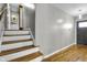 A bright hallway with wooden floors leads to a staircase with white risers and a dark front door at 5543 N Pennsylvania N St, Indianapolis, IN 46220