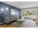 Cozy living room with bay window, comfortable grey seating, modern light fixture and dark blue accent wall at 5543 N Pennsylvania N St, Indianapolis, IN 46220