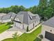 Aerial view of a well-maintained home with 3-car garage, green lawn and mature trees at 5572 Harness Dr, Greenwood, IN 46143
