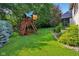 A backyard features a wooden playset, plush lawn, and established landscaping at 5572 Harness Dr, Greenwood, IN 46143