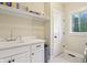 Well-lit laundry room with built-in shelving, sink, white cabinetry and updated fixtures at 5572 Harness Dr, Greenwood, IN 46143