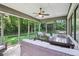 This screened porch includes an outdoor dining table, ceiling fan, and comfortable seating at 5572 Harness Dr, Greenwood, IN 46143