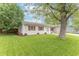Charming single-story home featuring white siding, red shutters, and a lush green lawn with mature trees at 5602 Northport Dr, Indianapolis, IN 46221