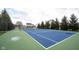 Outdoor tennis court with blue surface, surrounded by fencing and mature trees in a residential community at 589 Viking Warrior Blvd, Westfield, IN 46074