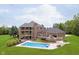 Expansive backyard featuring a pool, patio, and hot tub nestled within a well-manicured lawn and brick home at 6630 Travis Rd, Greenwood, IN 46143