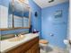 This bright bathroom features blue walls, a wood vanity, and a shower with a checkered curtain at 6737 Raritan Dr, Indianapolis, IN 46221
