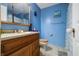 This bright bathroom features blue walls, a wood vanity, and a shower with a checkered curtain at 6737 Raritan Dr, Indianapolis, IN 46221