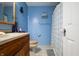 This bright bathroom features blue walls, a wood vanity, and a shower with a checkered curtain at 6737 Raritan Dr, Indianapolis, IN 46221
