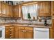 Classic kitchen featuring wood cabinets, modern faucet, white appliances, and natural light streaming through the window at 6737 Raritan Dr, Indianapolis, IN 46221