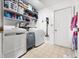This laundry room features a white washer and dryer, vinyl flooring, and shelving at 6737 Raritan Dr, Indianapolis, IN 46221