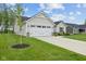Two-car garage with a concrete driveway and a well-kept lawn adds to the curb appeal of this home at 7051 E Bean Blossom Dr, Camby, IN 46113