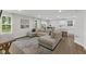 Open-concept living room with a large sectional sofa, hardwood floors, and views of the adjacent kitchen and dining area at 7051 E Bean Blossom Dr, Camby, IN 46113