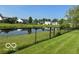Peaceful view of the backyard pond surrounded by a black chainlink fence and lush greenery at 7549 Stockard St, Indianapolis, IN 46239