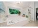 Bathroom featuring a soaking tub next to large bright window and glass enclosed shower at 8301 Reef Ct, Indianapolis, IN 46236