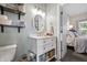 Well-lit bathroom with a vanity, shelves, and a view into the carpeted bedroom at 941 N Beville Ave, Indianapolis, IN 46201