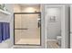 Tiled shower with glass door, shelf, and overhead shower head, adjacent to toilet room at 104 Perlican Dr, Cicero, IN 46034