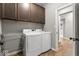 Well-equipped laundry room with dark wood cabinets and modern white washer and dryer at 104 Perlican Dr, Cicero, IN 46034