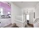 Upstairs hallway with wood floors and view into a pink bedroom with a ceiling fan at 10479 Dusty Rose Dr, Zionsville, IN 46077