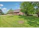 Expansive backyard with a lush lawn, mature trees, and a brick home featuring an attached three-car garage at 1121 N Cambridge Ct, Greenfield, IN 46140
