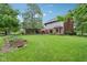 Expansive backyard with a large lawn, mature trees, and a view of the home's exterior and patio at 1121 N Cambridge Ct, Greenfield, IN 46140
