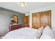 Bedroom featuring wooden closet doors, gray accent wall, carpet, and a dresser with mirror, creating a cozy and stylish atmosphere at 1121 N Cambridge Ct, Greenfield, IN 46140
