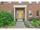 Charming home entrance featuring a bright yellow door with classic columns and beautiful landscaping at 1121 N Cambridge Ct, Greenfield, IN 46140